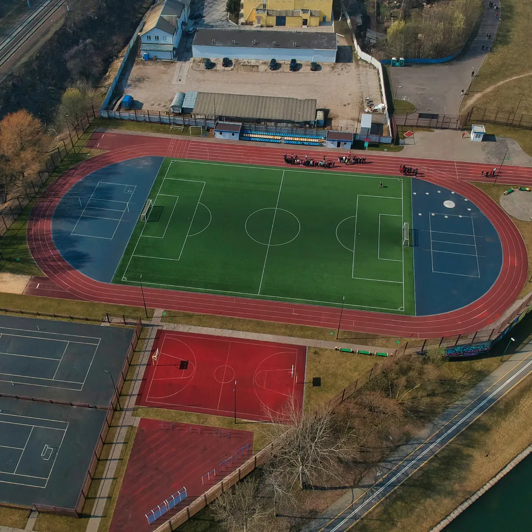 Een veelzijdige atletiekpiste omgeven door sportfaciliteiten, waaronder een tennisveld, basketbalveld, voetbalveld, hockey en meer, waardoor het een ideale locatie is voor diverse sportactiviteiten en recreatie.