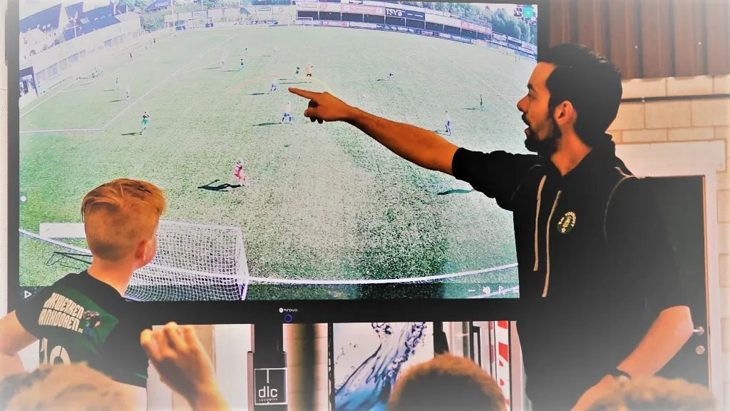 Een coach die aan het tactics board tips geeft aan de spelers.